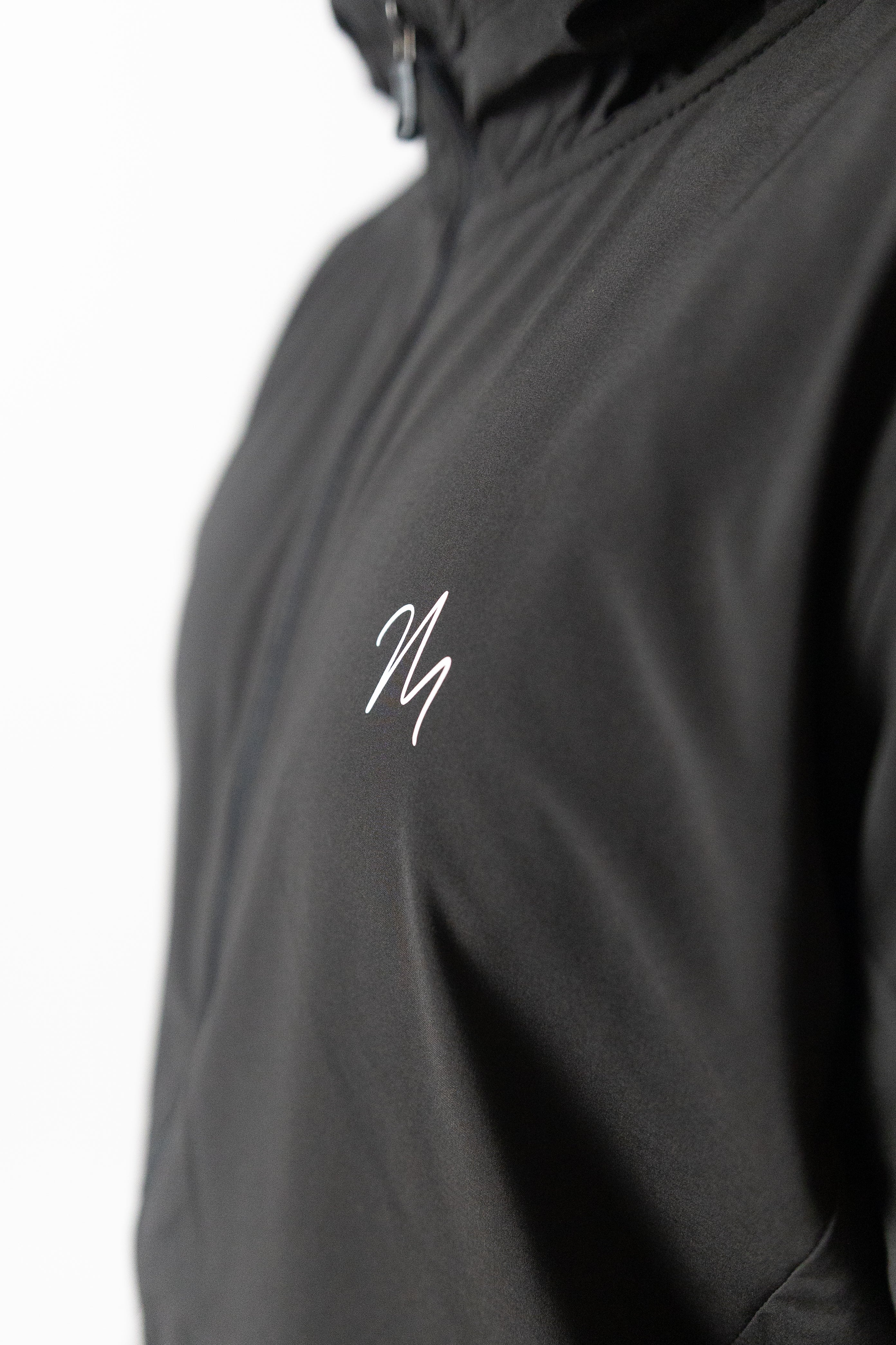 Image du survêtement Stockholm de Mauritti en noir, un ensemble zippé à capuche alliant style sportswear chic et confort. Confectionné en polyester et élasthanne, cet ensemble offre une grande flexibilité et un toucher doux. Il inclut des poches pratiques, une capuche ajustable, une fermeture éclair sur le devant, et des zips aux chevilles pour une touche moderne et fonctionnelle. Parfait pour un look décontracté au quotidien, cet ensemble est aussi adapté aux activités sportives.