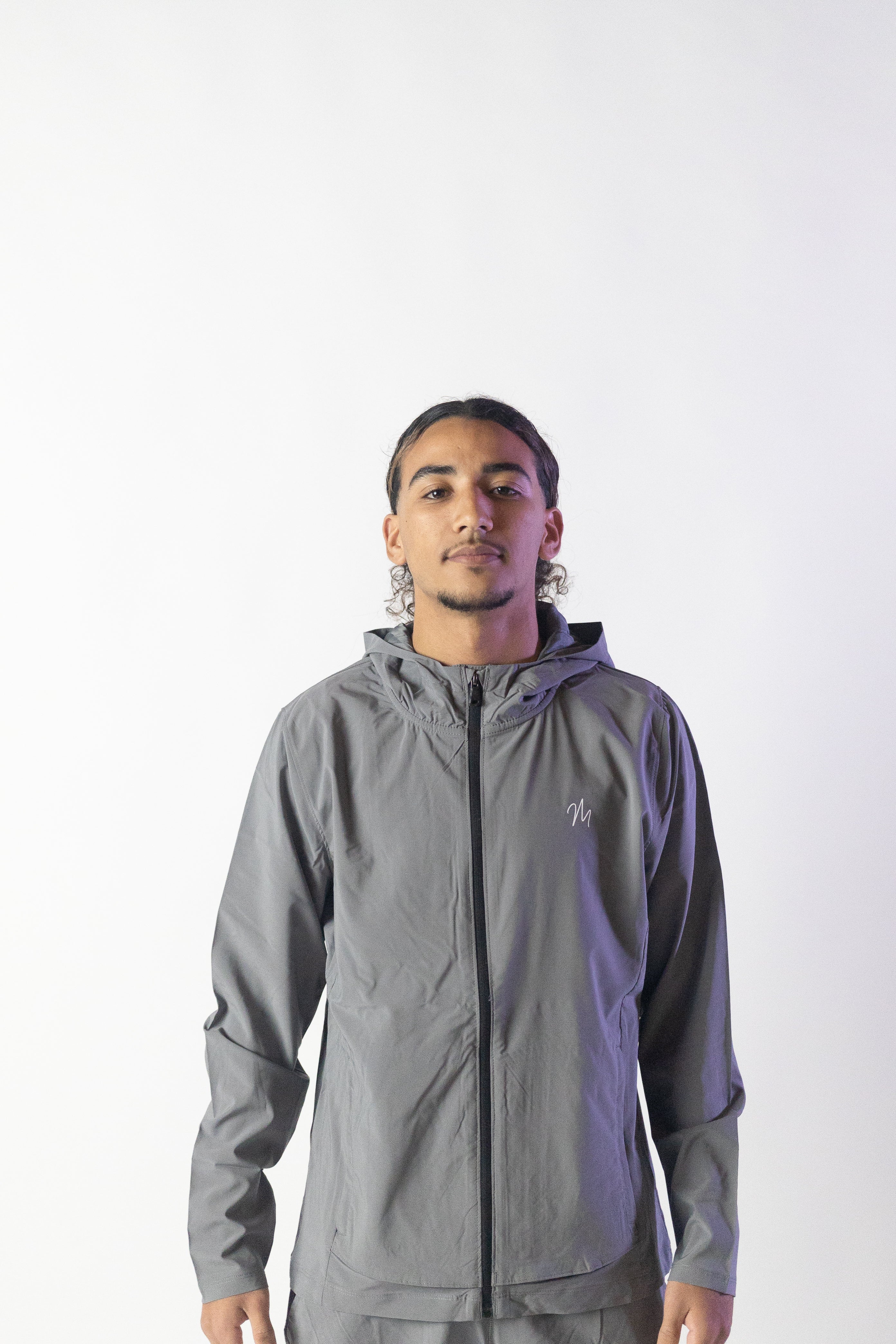 Image du survêtement Stockholm de Mauritti en gris, un ensemble zippé à capuche au style décontracté et moderne. Fabriqué en polyester et élasthanne, cet ensemble offre confort et flexibilité. Il comprend des poches pratiques, une capuche ajustable, une fermeture éclair sur le devant, et des zips aux chevilles pour un look unique et fonctionnel. Idéal pour un style sportswear chic, cet ensemble est parfait pour un usage quotidien ou des sorties décontractées. Le mannequin mesure 1m77, pèse 80kg.