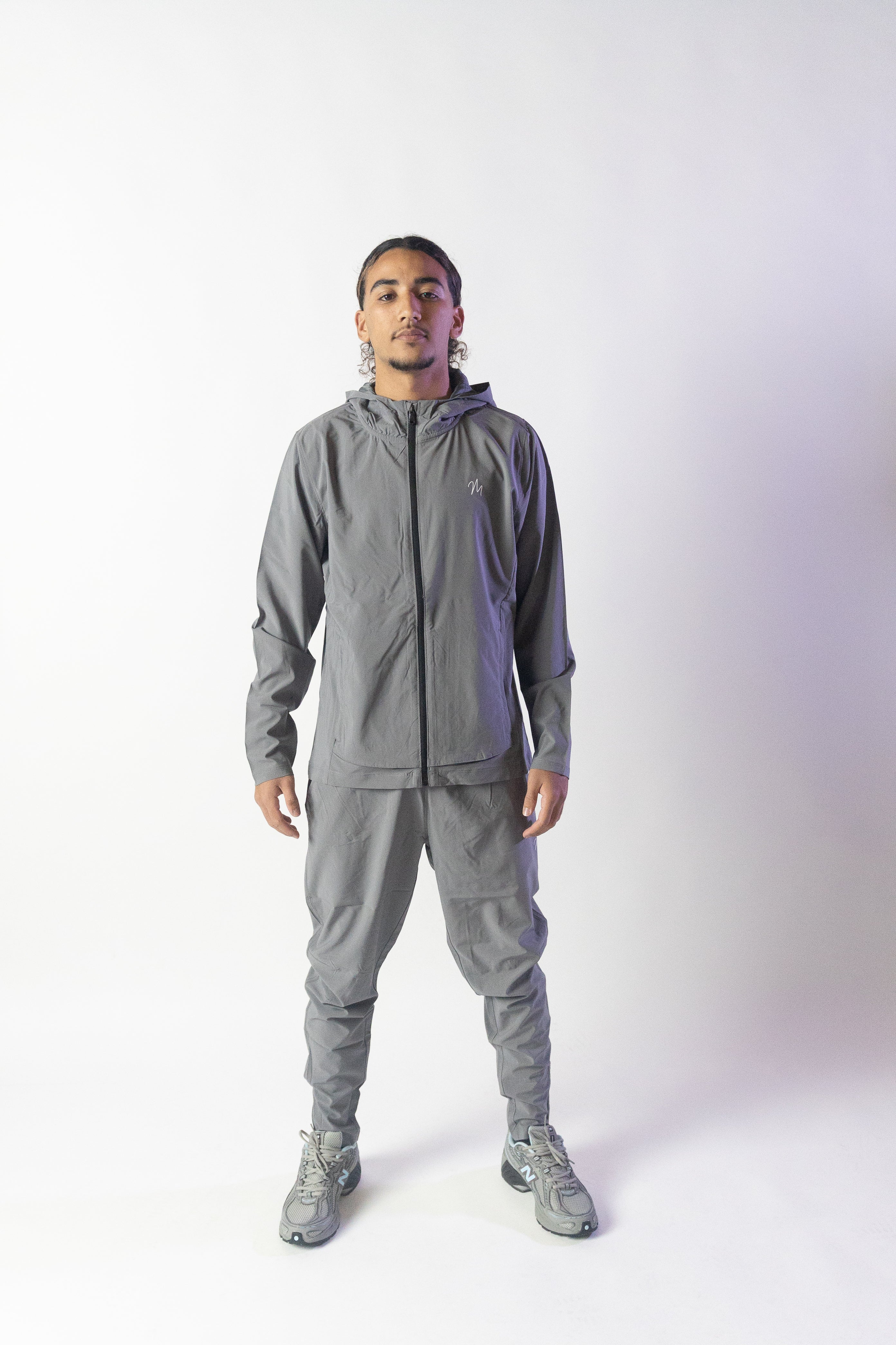 Image du survêtement Stockholm de Mauritti en gris, un ensemble zippé à capuche au style décontracté et moderne. Fabriqué en polyester et élasthanne, cet ensemble offre confort et flexibilité. Il comprend des poches pratiques, une capuche ajustable, une fermeture éclair sur le devant, et des zips aux chevilles pour un look unique et fonctionnel. Idéal pour un style sportswear chic, cet ensemble est parfait pour un usage quotidien ou des sorties décontractées. Le mannequin mesure 1m77, pèse 80kg.