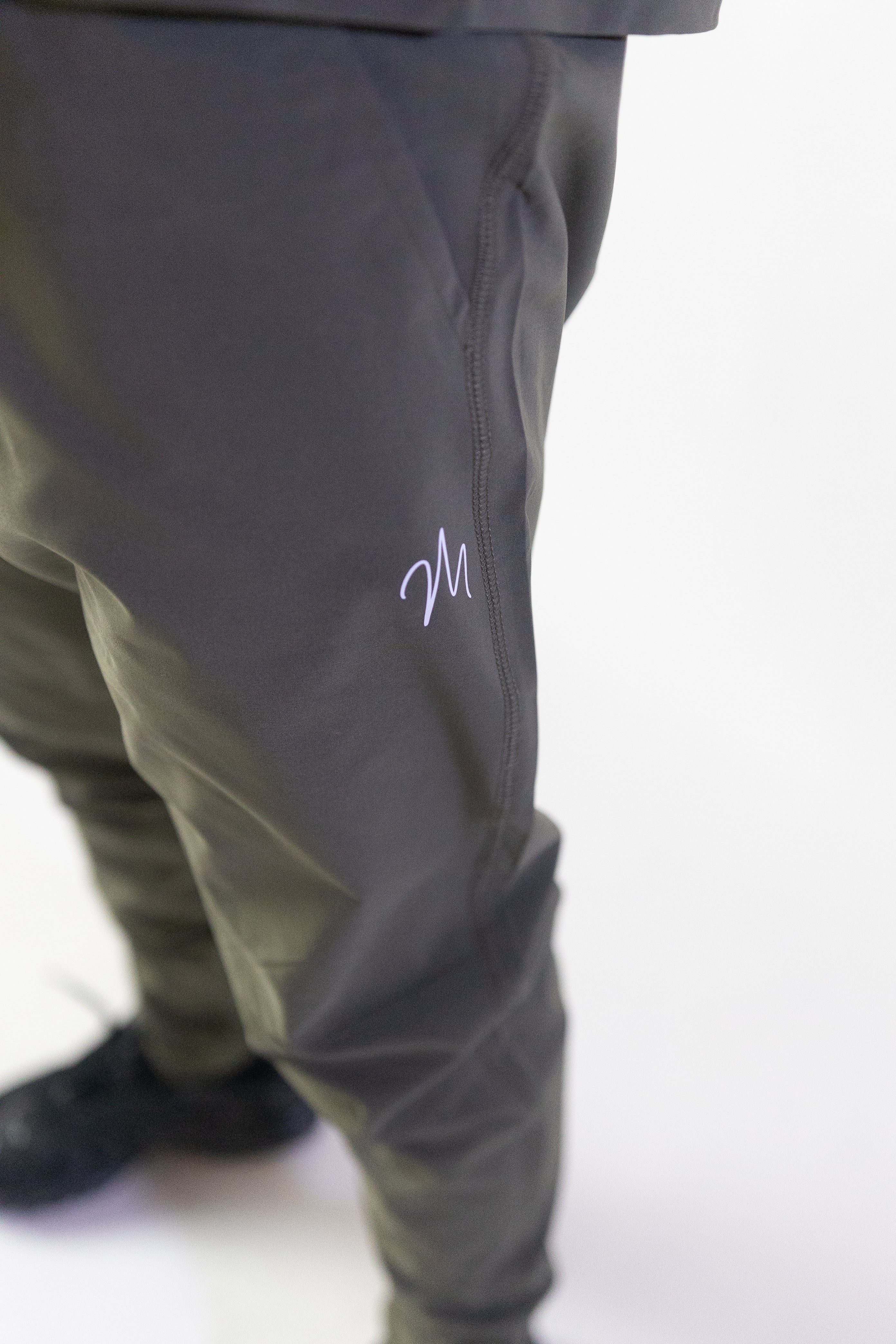 Image du survêtement Stockholm de Mauritti en kaki, un ensemble zippé à capuche combinant style décontracté et confort sportswear. Ce modèle, fabriqué en polyester et élasthanne, offre une grande souplesse et un toucher agréable. Il est équipé de poches pratiques, d'une capuche ajustable, d'une fermeture éclair sur le devant, ainsi que de zips aux chevilles pour une finition moderne et fonctionnelle.