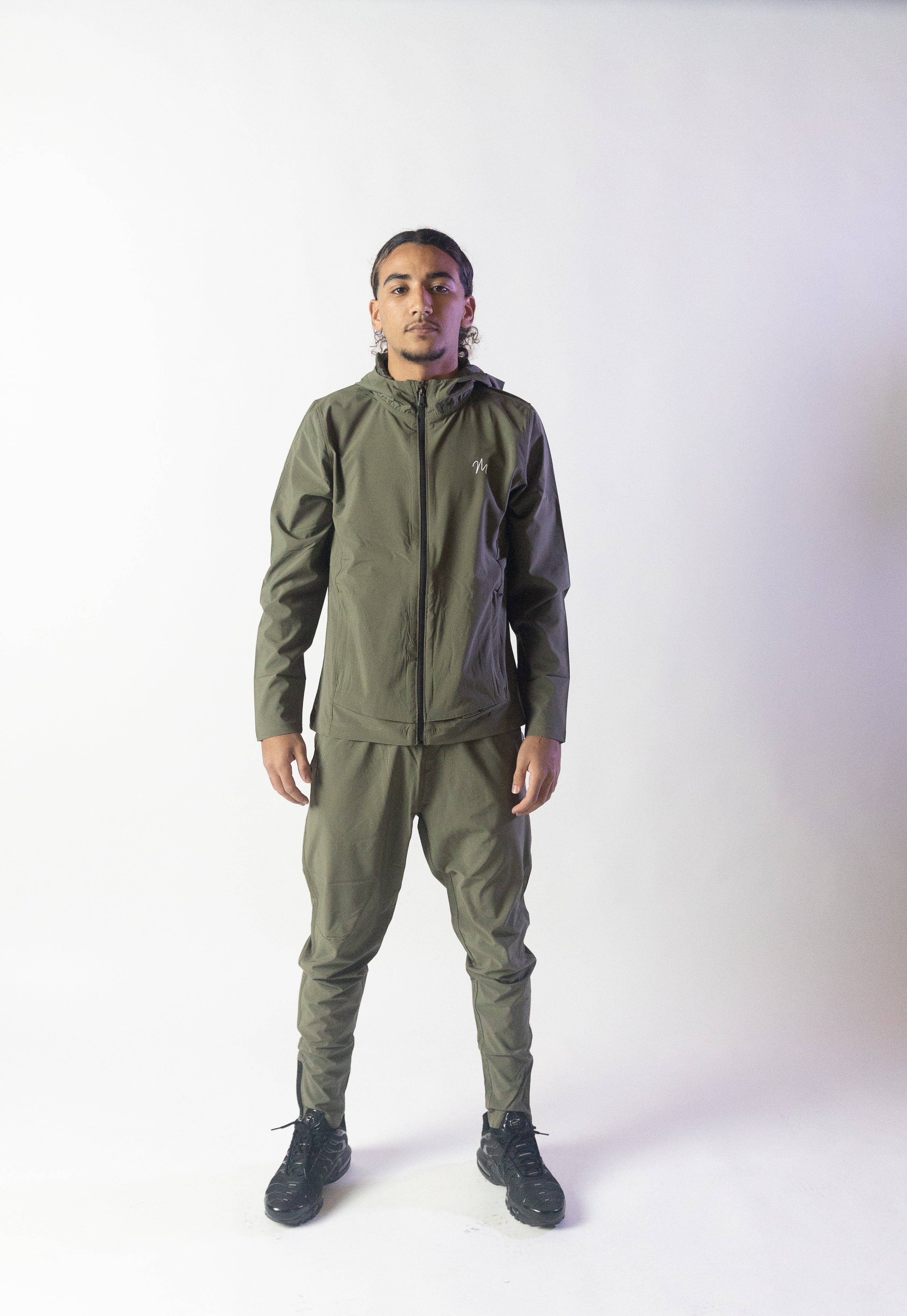 Image du survêtement Stockholm de Mauritti en kaki, un ensemble zippé à capuche combinant style décontracté et confort sportswear. Ce modèle, fabriqué en polyester et élasthanne, offre une grande souplesse et un toucher agréable. Il est équipé de poches pratiques, d'une capuche ajustable, d'une fermeture éclair sur le devant, ainsi que de zips aux chevilles pour une finition moderne et fonctionnelle.
