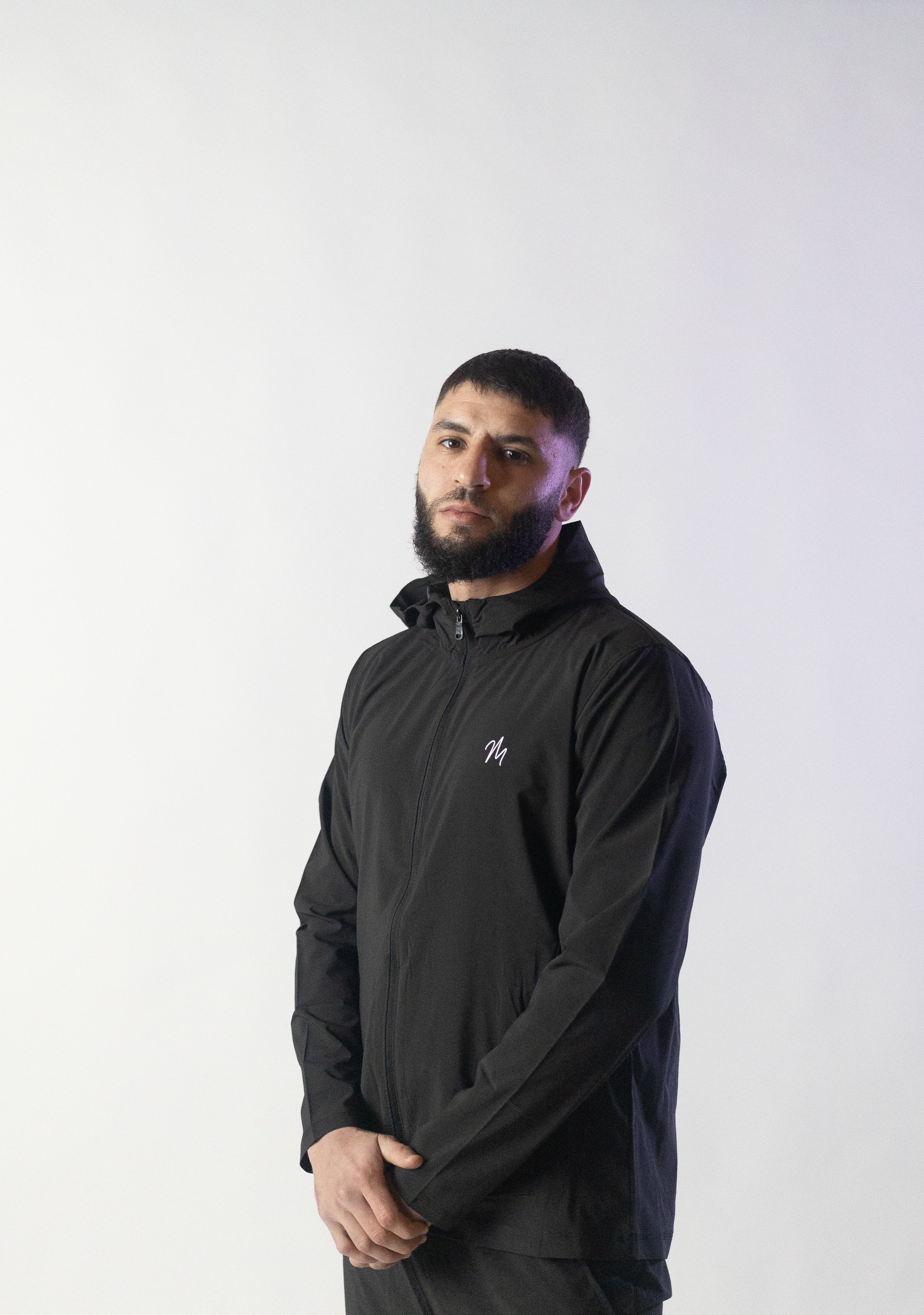 Image du survêtement Stockholm de Mauritti en noir, un ensemble zippé à capuche alliant style sportswear chic et confort. Confectionné en polyester et élasthanne, cet ensemble offre une grande flexibilité et un toucher doux. Il inclut des poches pratiques, une capuche ajustable, une fermeture éclair sur le devant, et des zips aux chevilles pour une touche moderne et fonctionnelle. Parfait pour un look décontracté au quotidien, cet ensemble est aussi adapté aux activités sportives.